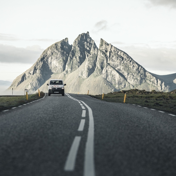Campervan on the paved road with view on the snowy mountain in the background